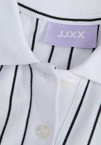 Polo blanc avec des rayures verticales noires, présentant un col à côtelage, trois boutons et une étiquette lavande affichant "JJXX".