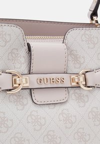 Sac à main gris clair avec un motif de logo en relief, doté de quincaillerie dorée et d'une fermeture éclair, fabriqué en matériau texturé avec des accents en cuir lisse.