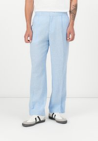 Light blue, striped linen pants with a relaxed fit and elastic waistband. Features pressed pleats and a straight leg design.