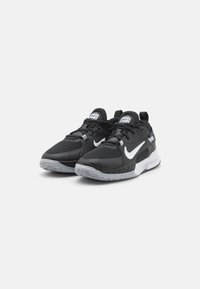 Čierne športové topánky s vrchnou časťou z sieťoviny, bielym logom Nike a šedou gumovou podrážkou. Obsahujú polstrovaný jazyk a otvory pre šnúrky.