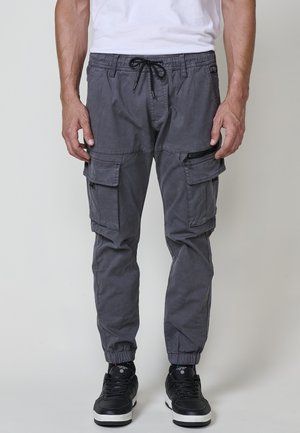 Pantalones cargo grises de mezcla de algodón con puños y cinturilla elásticos. Cuenta con múltiples bolsillos y un bolsillo lateral con cremallera.