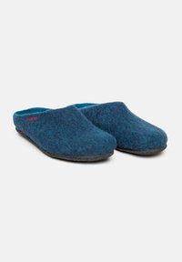 Pantofole di lana di colore blu scuro con una texture in feltro morbido, forma arrotondata e interno di un blu chiaro a contrasto. Presentano una suola in gomma nera.