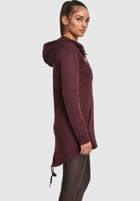 Bordo dolga jopa z žepi spredaj, nastavljivim vrvico in gladko teksturo. Ima sproščen kroj in podaljšano dolžino.