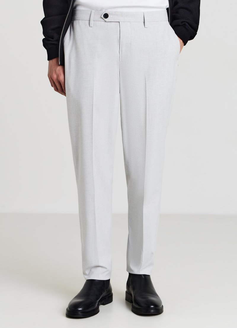 Hellgraue maßgeschneiderte Hosen mit einem strukturierten Muster, geradem Schnitt, einzelnen Falten und einem Knopfverschluss, kombiniert mit schwarzen Knöchelstiefeln.