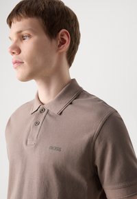 Brun polo skjorte laget av bomull, med klassisk krage, to-knaps placket og subtil "BOSS" logo brodert på brystet.