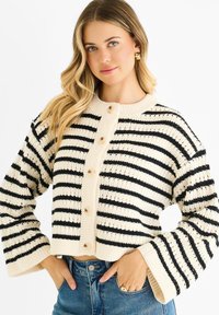 Knitted cropped cardigan in cream and black stripes, featuring a round neckline, long bell sleeves, and button closure with light-colored buttons.
