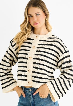 Knitted cropped cardigan in cream and black stripes, featuring a round neckline, long bell sleeves, and button closure with light-colored buttons.