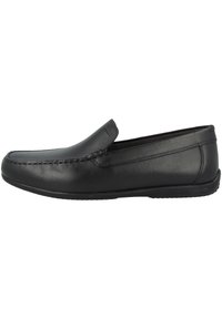 Mocassin en cuir noir sans lacets avec détail moc toe cousu et semelle basse plate, présenté en profil latéral sur fond blanc.