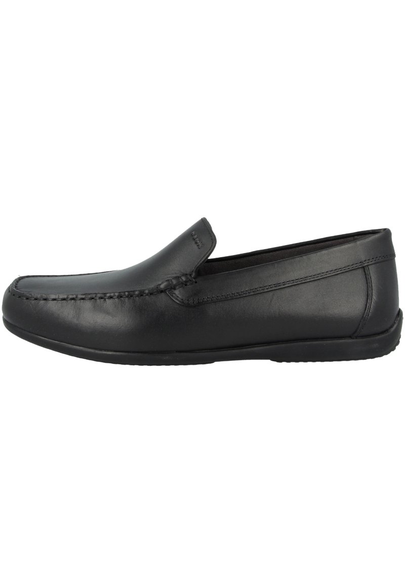 Mocassin en cuir noir sans lacets avec détail moc toe cousu et semelle basse plate, présenté en profil latéral sur fond blanc.
