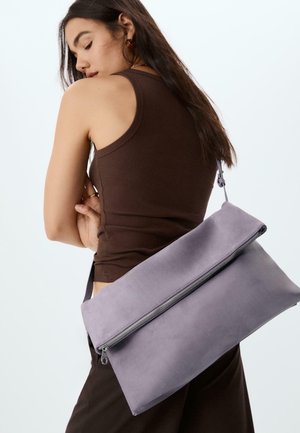 Borsa a spalla in suede viola con chiusura a zip, forma rettangolare e una lunga tracolla, indossata sulla spalla su uno sfondo neutro.