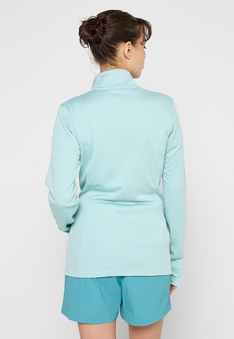 Hellblauer, langärmeliger Pullover mit hohem Kragen, strukturiertem Stoff und tailliertem Design. Zusammen mit passenden Shorts kombiniert.