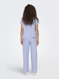 Top a maniche corte a righe blu chiaro e pantaloni larghi abbinati, caratterizzati da una vestibilità comoda e una texture liscia, abbinati a calzature bianche.