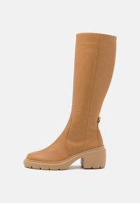 Bottes hauteur genou en cuir lisse couleur beige, avec un bout arrondi, une semelle beige épaisse et une fermeture éclair latérale pour un enfilage facile.