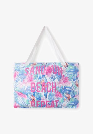 Borsa mare con motivo floreale colorato, sfondo bianco, manici trasparenti e testo rosa acceso: "SABBIA, SPIAGGIA, RIPETI."