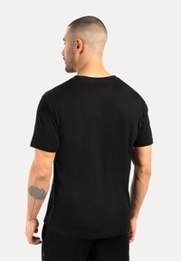 Czarna bawełniana koszulka z krótkim rękawem, okrągłym dekoltem i bocznymi rozcięciami. Posiada prosty design o gładkiej fakturze.