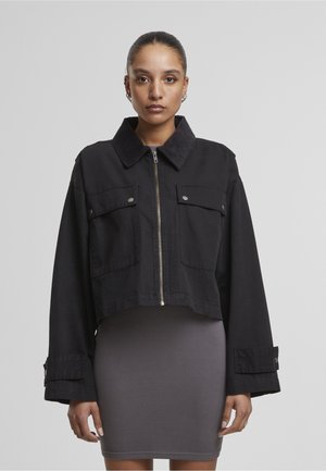 Giacca di jeans nera corta con colletto in velluto a coste, due tasche sul petto e maniche larghe. Caratterizzata da dettagli in argento e chiusura frontale con zip.