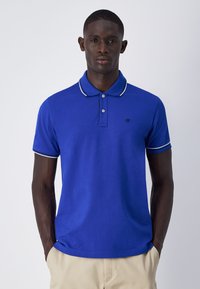 Herren Poloshirt in Blau aus Baumwolle. Verfügt über ein Design mit Kragen, einer Zwei-Knopfleiste und weißen Streifenakzenten am Kragen und den Ärmeln.