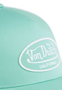 Gorra verde claro con una superficie texturizada, que presenta un parche de logo bordado en blanco que dice "Von Dutch CALIFORNIA."