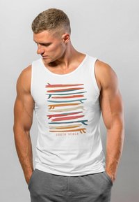 Weißes Tanktop mit einem bunten abstrakten Design in Bändern aus Rot, Blaugrün, Orange und Beige, mit dem Text "SOUTH BEACH" am unteren Rand.