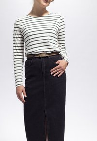 Randig långärmad skjorta i vitt med mörkgröna ränder, ihop med en högmidjad svart denimkjol med en sprund fram och bälte.