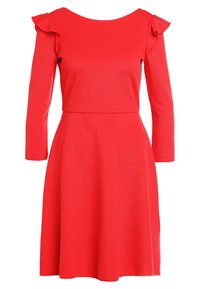 Robe rouge à manches longues, ornée de détails volants aux épaules, avec un corsage ajusté et une jupe évasée, fabriquée dans un tissu doux.