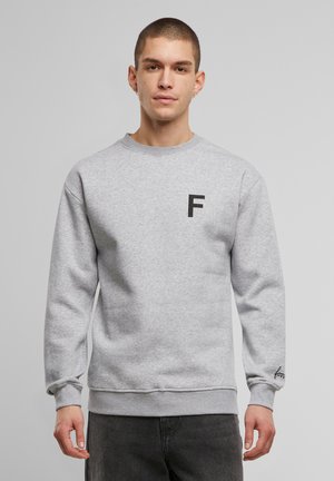 Grauer Sweatshirt mit Rundhalsausschnitt, ausgestattet mit einem schwarzen "F"-Logo auf der Brust und gesticktem Detail am Bündchen. Glatte Textur, lockere Passform.