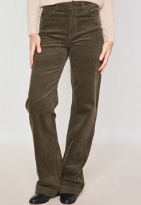 Pantalons en velours côtelé vert olive avec une coupe droite, dotés d'une taille haute, de poches avant et d'une texture côtelée subtile.