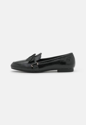 Sort læder loafer med lav hæl og dekorativ rem samt sløjf detalje på toppen, vist i sideprofil mod hvid baggrund.