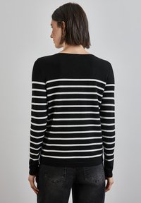 Maglione a righe bianche e nere con scollatura rotonda e tessuto testurizzato, con maniche lunghe e orlo aderente, mostrato da dietro.