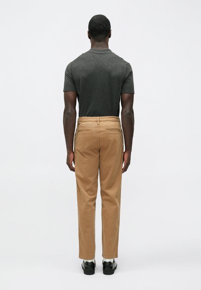Dark gray short-sleeve shirt paired with tan chinos, featuring a straight cut and back pockets, complemented by black shoes.