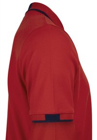 Camiseta polo roja con un tejido texturizado, un cuello clásico y detalles en azul marino en el cuello y los dobladillos de las mangas.