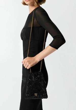 Sac à main en perles noires avec une ouverture à cordon et une bandoulière en chaîne dorée, présentant un accent de logo à l'avant. Vue de côté en angle.