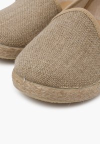 Espadrilles en color beige con parte superior de tela texturizada y suela de yute trenzada. Punta redondeada y línea superior elástica para un ajuste seguro.