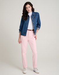 Τζάκετ από τζιν με σχέδιο με κουμπιά σε σκούρο μπλε, συνδυασμένο με ανοιχτό ροζ παντελόνι ίσιας γραμμής. Λευκά αθλητικά παπούτσια ολοκληρώνουν την εμφάνιση.