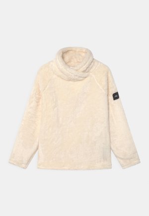 Kremowy polarowy pulower z szerokim kapturem typu komin, długimi rękawami raglanowymi i czarną metką na lewym rękawie. Miękka, teksturowana powierzchnia.