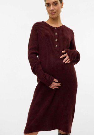 Robe de maternité côtelée bordeaux avec un col rond, des manches longues et des détails de boutons au niveau de la poitrine, atteignant la longueur mi-mollet.