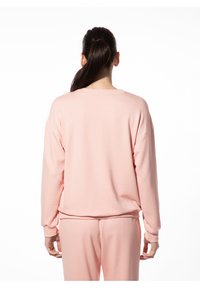 Lichtroze sweatshirt met lange mouwen, een ronde hals en ribgebreide manchetten. De stof lijkt zacht en comfortabel met een losse pasvorm.