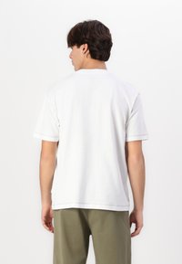 Hvit bomulls T-skjorte med avslappet passform, korte ermer og rett nedkant. Minimalistisk design med synlige sømdetaljer.