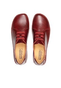 Zapatos de cuero rojo con punta redondeada, costuras texturizadas alrededor de los bordes y bandas elásticas en la parte superior para un ajuste flexible.
