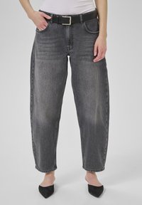 Jean en denim gris taille haute, coupe ample, avec poches avant, agrémenté d'une ceinture noire et d'une boucle en argent.