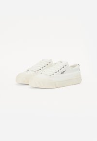 Vita canvas sneakers med rund tå, gummisula och matchande snören. Dekorerade med en liten svart logotyp på sidan och texturerade detaljer.