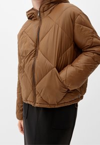 Brun quiltad pufferjacka med huva, som har dragkedjestängning, diagonala sömmar och elastiska muddar.