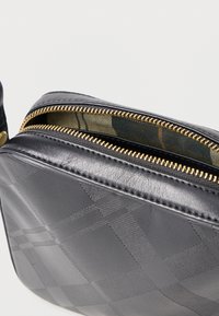 Fekete bőrtáska strukturált rombuszmintával, arany cipzárral és mintás belső béléssel.