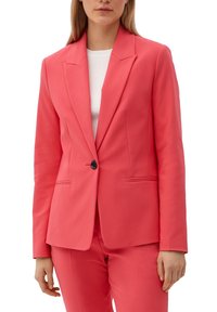 Korálově růžový blazer s jedním knoflíkem a klopovými límci. Obsahuje dvě přední kapsy a hladký, strukturovaný materiál. Nositý přes bílý top.