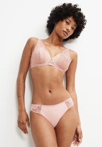 Ljusrosa spetsbehå med blommönster och mjuka kupor, matchad med underkläder som har spetsdetaljer. Mjuk textur, justerbara band.