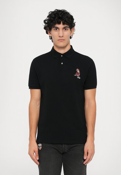 Polo negro de corte ajustado, hecho de algodón. Presenta un diseño bordado en rojo en el pecho y detalles sutiles de botones en el cuello.