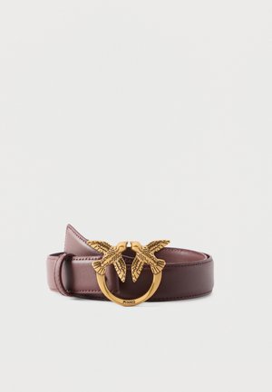 Bruine leren riem met gouden ronde gesp met daarop twee reliëf vogels die elkaar aankijken, gegraveerd met het "PINKO" logo.
