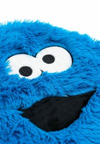 Giocattolo di peluche blu con una texture soffice, grandi occhi bianchi con pupille nere e una bocca nera larga con un'espressione sorridente.