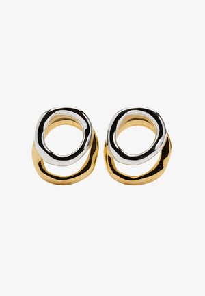 Kolczyki w odcieniach złota i srebra o abstrakcyjnym, splecionym kształcie, z gładkimi metalicznymi wykończeniami i zaokrąglonymi krawędziami.