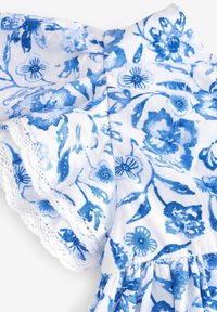 Weißes Kleid aus Stoff mit blauen Blumenmustern, rüschigen Ärmeln und Spitzenbesatz, gesammelter Taille und strukturierter Oberfläche.